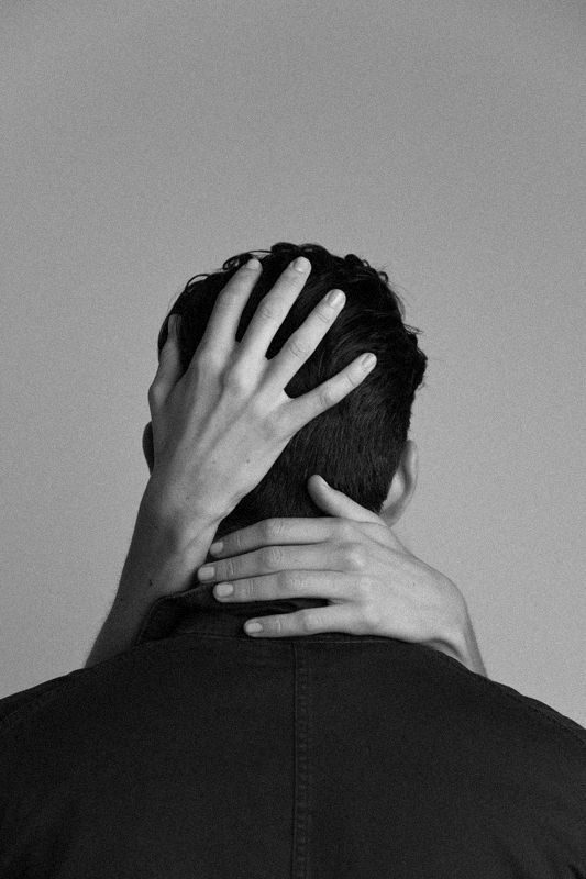 Black-and-white photo of a woman’s hands resting on the back of her partner’s head and neck.